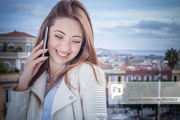 Junge Frau auf dem Dach chattet auf dem Smartphone  Cagliari  Sardinien  Italien