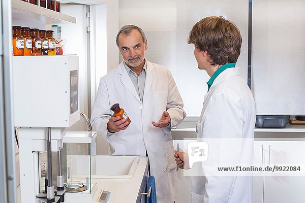 Pharmacist advising trainee on medicine in pharmacy