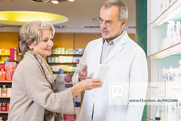 Pharmacist advising senior woman on medicine in pharmacy