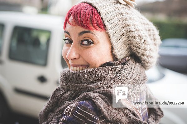 Porträt einer jungen Frau  die über die Schulter schaut  lächelnd  Winterkleidung tragend