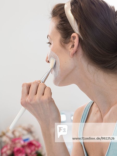 Mid Erwachsene Frau feuchtigkeitsspendende Gesicht mit Make-up-Pinsel