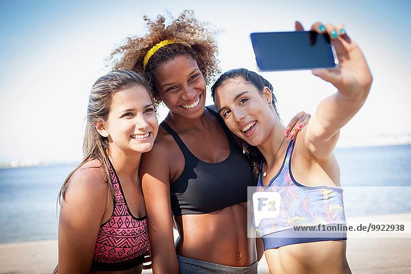 Three young women photographing themselves with phone