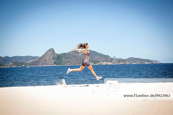 Young woman jumping on beach  Rio de Janeiro  Brazil