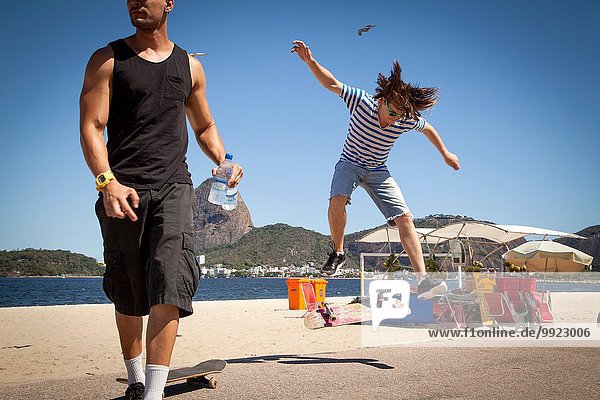Young man doing jump on skateboard  while friend looks away