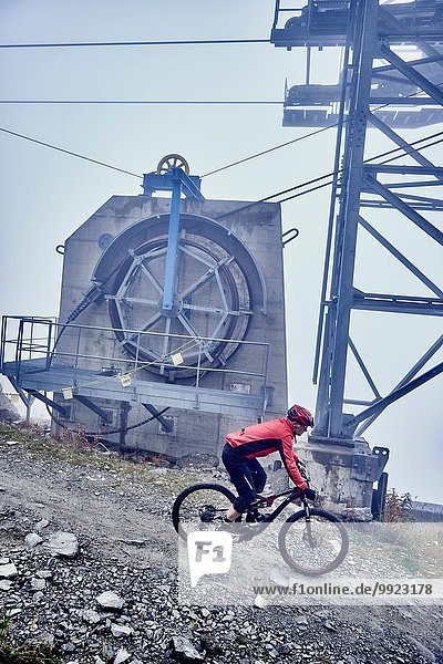 Erwachsener Mann Mountainbiken an der Seilbahn vorbei  Wallis  Schweiz