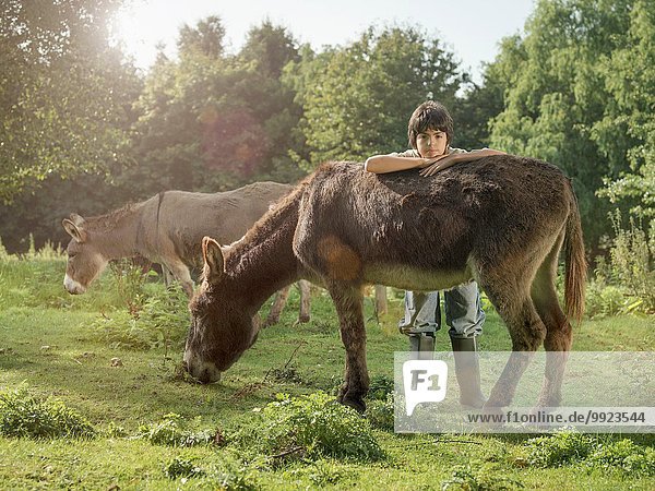 Boy with donkey in field portrait