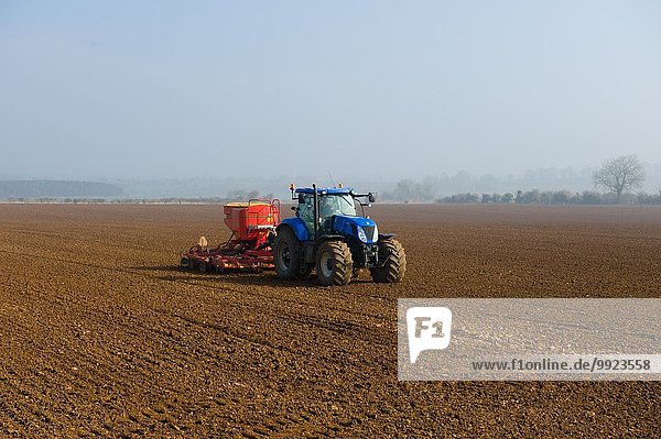 Traktor-Saatgut im gepflügten Feld am nebligen Morgen