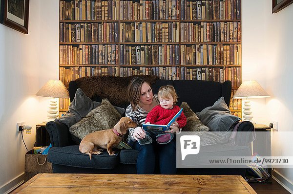 Mutter liest Buch an Sohn auf Sofa