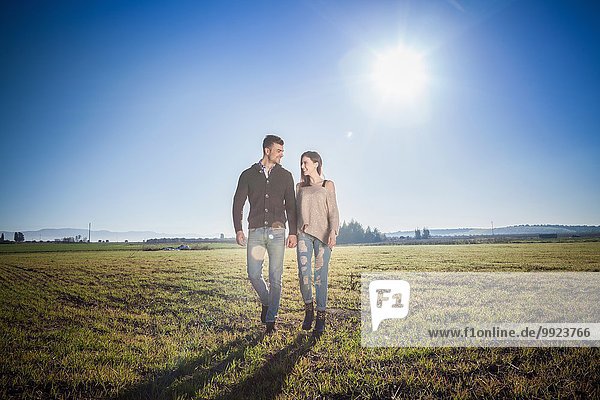 Young couple holding hands in field