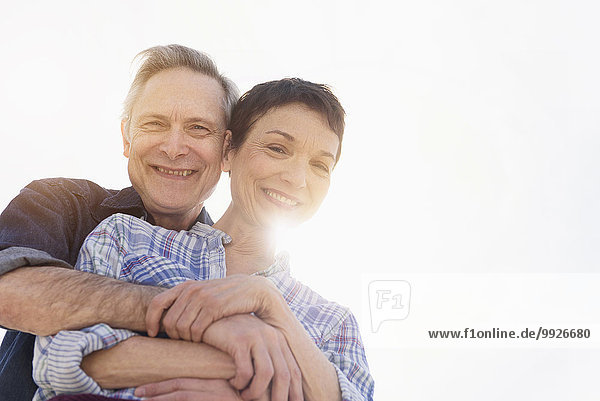 Portrait of smiling senior couple embracing in sunlight