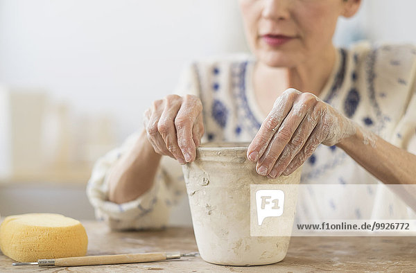 Senior woman making flower pot at workshop