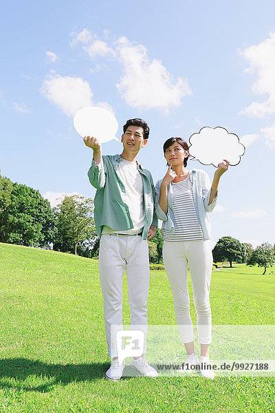 Happy Japanese couple with whiteboards in a city park