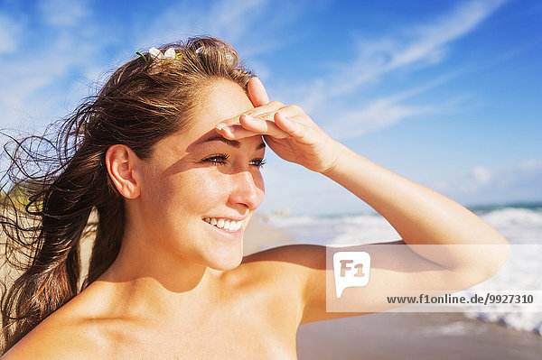 Woman on beach shielding eyes