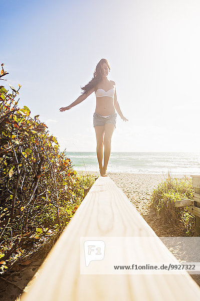 Young woman balancing on boardwalk