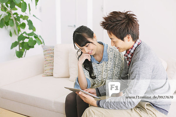 Young adult couple relaxing with tablet on the sofa