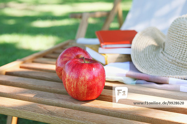Apples and straw hat on deck chair in a city park