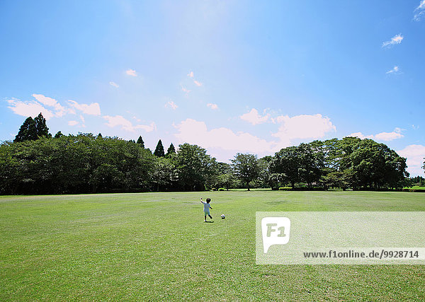 Japanese young boy playing soccer in a city park