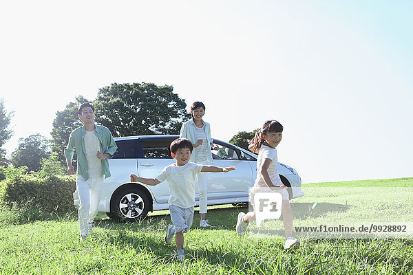 Happy Japanese family with car in a city park