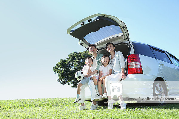 Happy Japanese family with car in a city park
