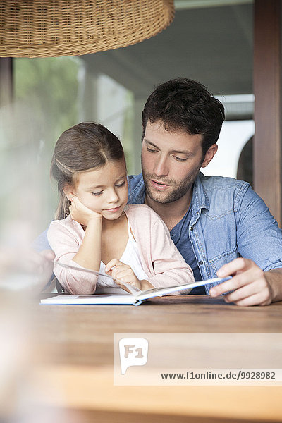 Father and young daughter reading together