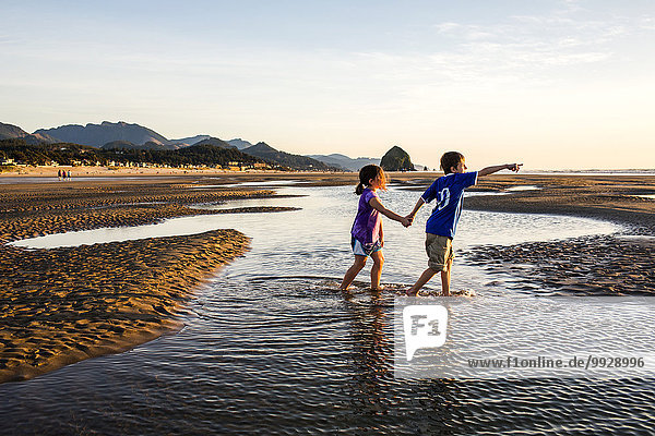 Caucasian children walking in tide pools on beach  Cannon Beach  Oregon  United States