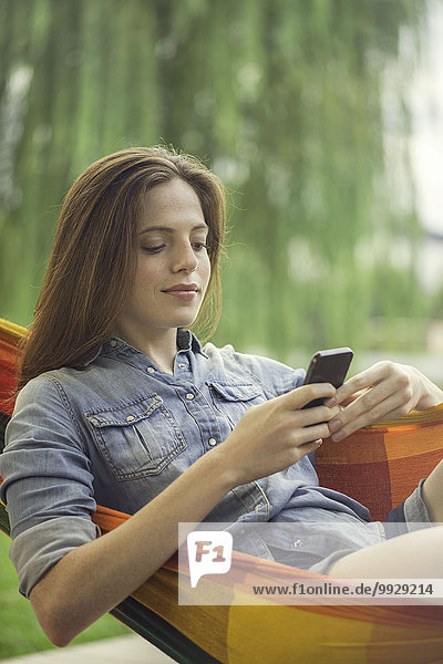 Frau entspannt in der Hängematte mit Smartphone