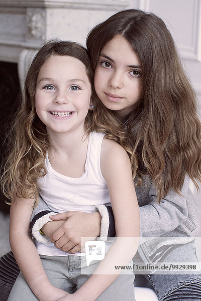 Mädchen umarmt jüngere Schwester  Portrait