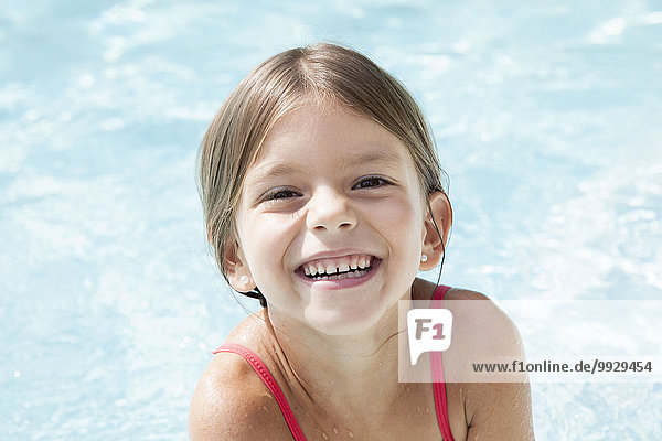 Little girl in pool  smiling cheerfully  portrait