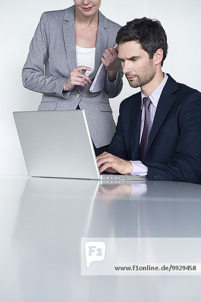 Businessman working on laptop computer  colleague looking over his shoulder