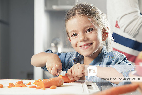 Little girl slicing carrots in kitchen  portrait