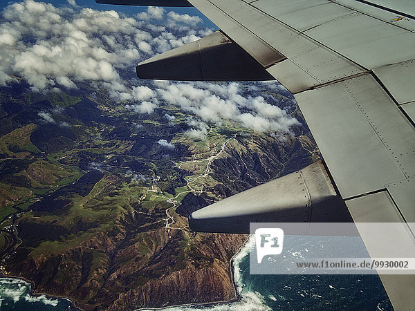 Aerial view of airplane wing flying over coastline