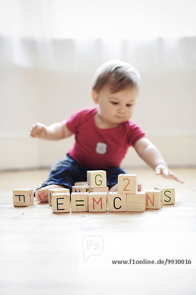 Baby boy playing with toy blocks arranged to read ''E=mc2'''.