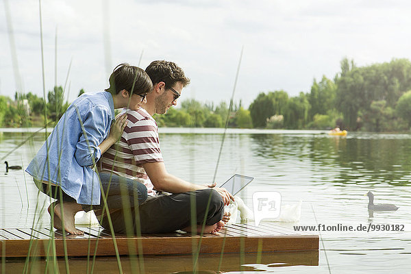 Couple using laptop computer on dock