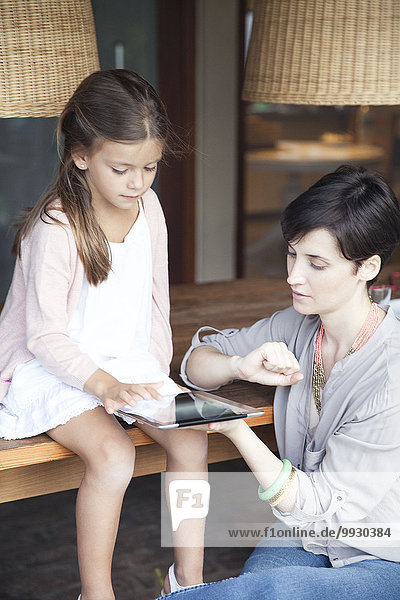 Mother and young daughter using digital tablet together