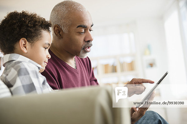 Mixed race grandfather and grandson using digital tablet