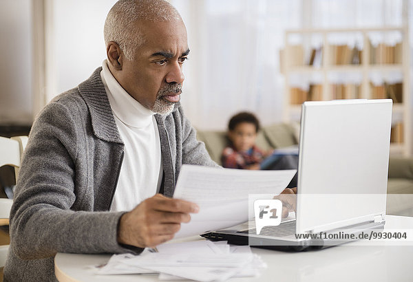 Mixed race man paying bills on laptop