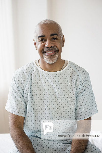 Mixed race older man sitting on hospital bed