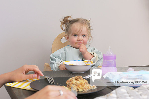 Baby sitting in high chair at table having meal