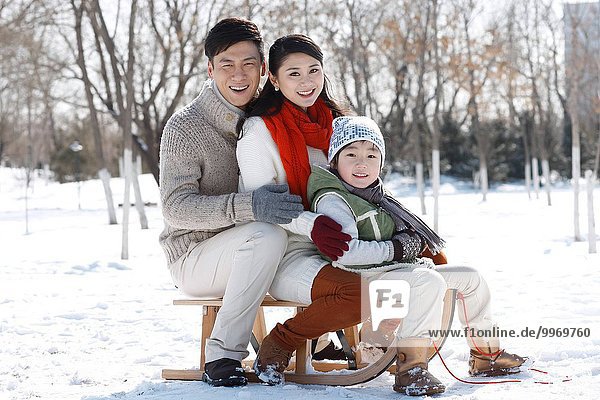 Oriental family sitting on a sled
