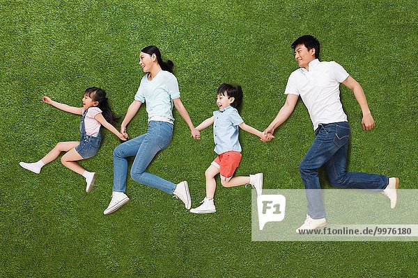 A family of four lying on the grass do running posture