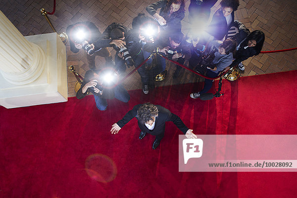 Paparazzi photographers photographing celebrity at red carpet event