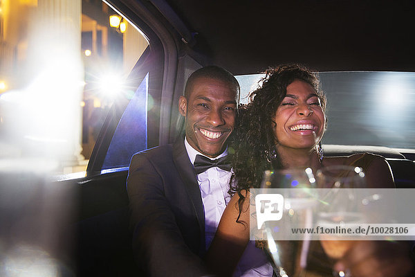 Lachendes Promi-Paar trinkt Champagner in der Limousine beim Red Carpet Event