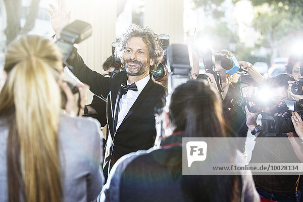 Celebrity waving at paparazzi photographers at event
