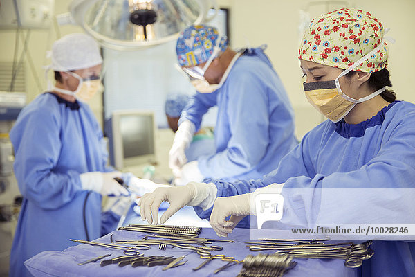 Surgeon at tray of surgical scissors in operating room