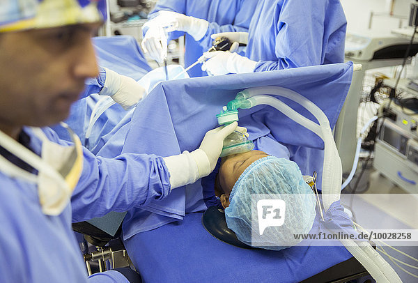 Anästhesist mit Sauerstoffmaske über dem Gesicht des Patienten im Operationssaal