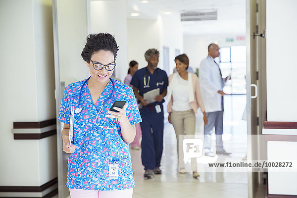 Nurse texting on cell phone in hospital corridor