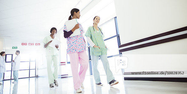 Krankenschwestern beim Sprechen und Gehen im Krankenhausflur