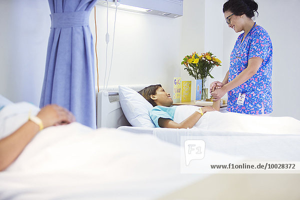 Nurse holding hands with patient in hospital room