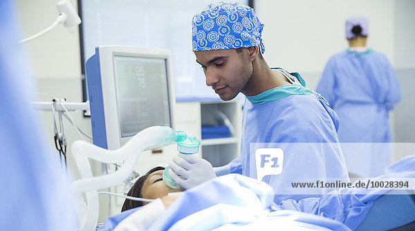 Anästhesist mit Sauerstoffmaske über dem Gesicht des Patienten im Operationssaal