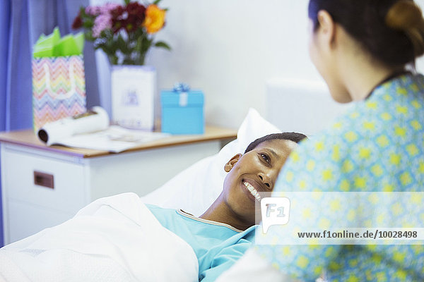 Smiling patient in hospital bed smiling at nurse
